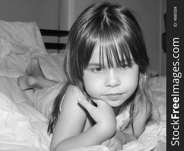 Sad little girl laying on a bed with a thoughtful expression. Sad little girl laying on a bed with a thoughtful expression.