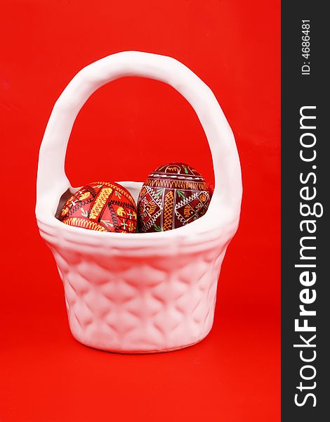 Two easter eggs in white basket over red