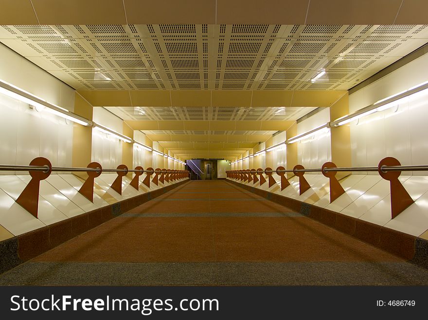 A pedestrian tunnel at a commuter rail station, with a colorful design including tinted concrete. A pedestrian tunnel at a commuter rail station, with a colorful design including tinted concrete