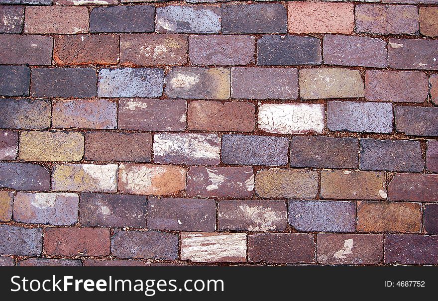 Closeup of worn, old brick paving found on a sidewalk.