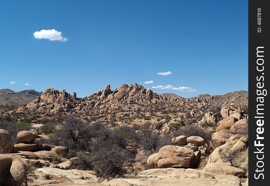 A landscape shot of the desert, with rocks, blue sky, and clouds. A landscape shot of the desert, with rocks, blue sky, and clouds.