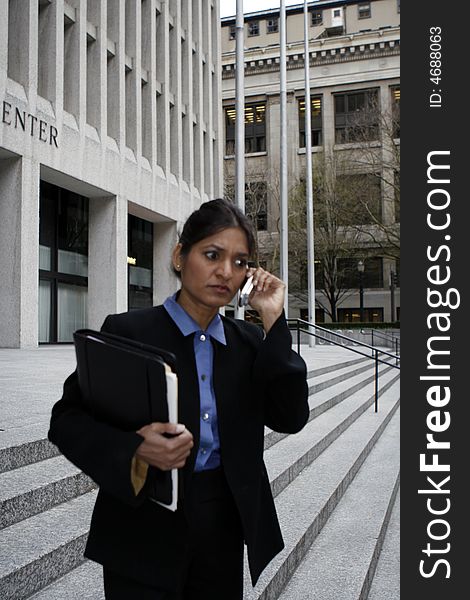 Executive Indian woman talking on a cellphone dressed in a black suit. Executive Indian woman talking on a cellphone dressed in a black suit.