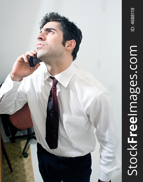 Business man looking up as he uses the phone. Isolated against a grey background. Business man looking up as he uses the phone. Isolated against a grey background