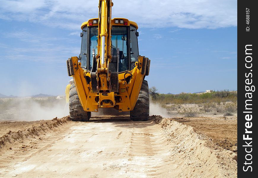 Shot of a backhoe driving down a dusty desert road. Shot of a backhoe driving down a dusty desert road.