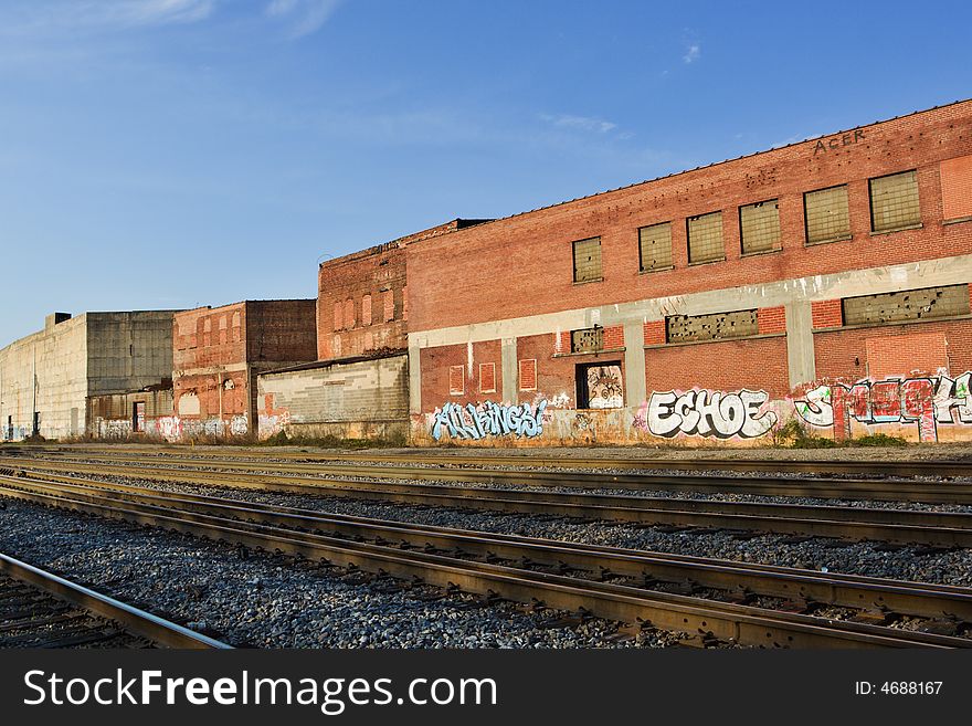 Photo of old brick warehouses with graffiti along railroad tracks. Photo of old brick warehouses with graffiti along railroad tracks