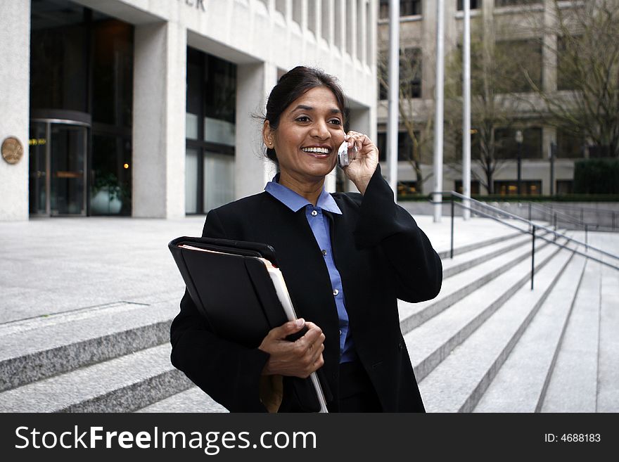 Exceutive Indian woman talking on a cellphone dressed in a black suit. Exceutive Indian woman talking on a cellphone dressed in a black suit.