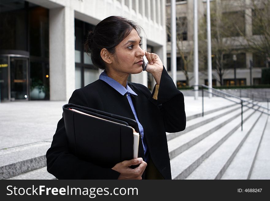 Executive Indian woman talking on a cellphone dressed in a black suit. Executive Indian woman talking on a cellphone dressed in a black suit.