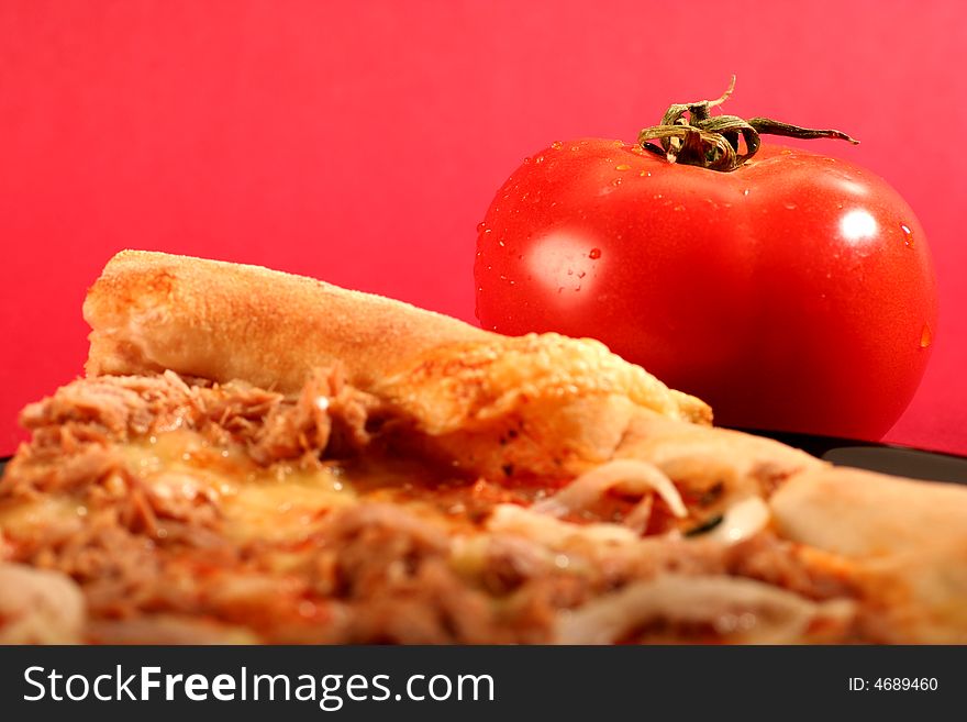 Pizza with a tomato on a red background.