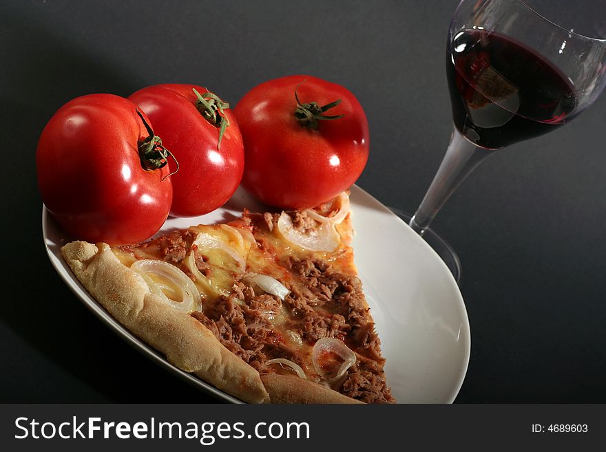 Pizza with tomatoes a glass wine on a black background.