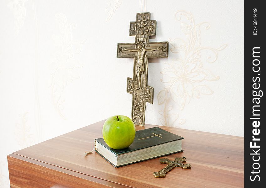 Holy bible with green apple and two crosses on the brown wooden table