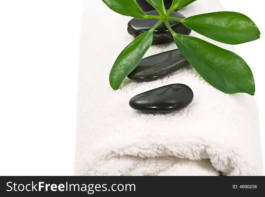 Therapy stones and green leaves on towel on white background. Therapy stones and green leaves on towel on white background