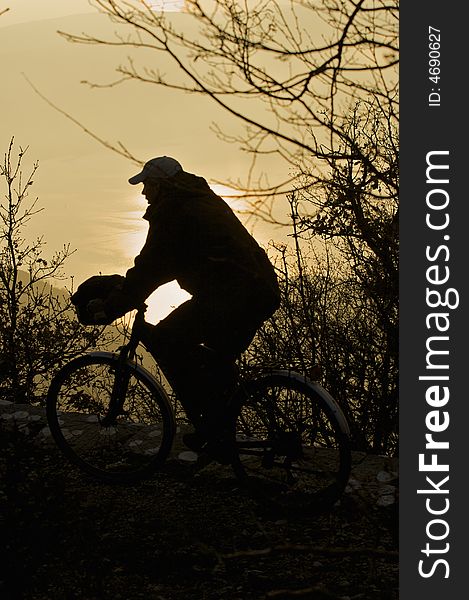 Silhouette of man on a bicycle in forest at sunset in the background. Silhouette of man on a bicycle in forest at sunset in the background