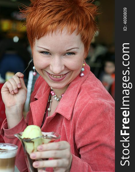 Woman eating ice-cream in cafe and thoughtfully looks afar