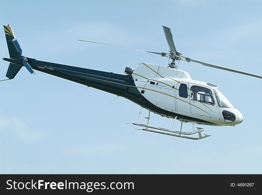 Small, blue and white, passenger helicopter mid-air. Small, blue and white, passenger helicopter mid-air