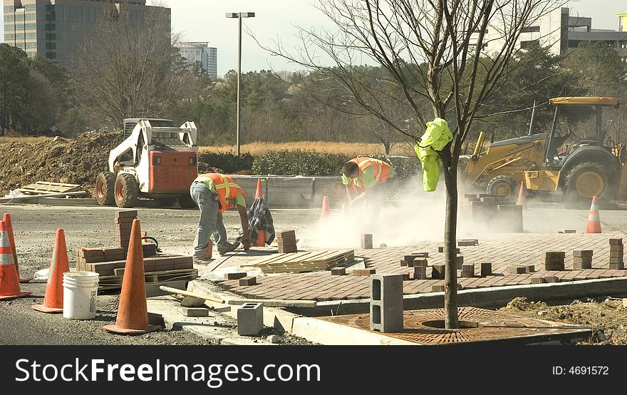 Workers using a grinder on a new concrete installation at a construction site. Workers using a grinder on a new concrete installation at a construction site