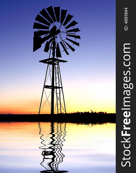 Wind pump silhouette with reflection