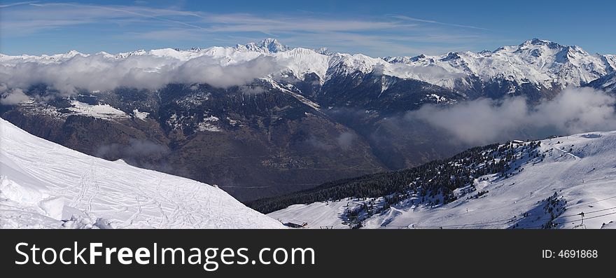 A panoramic view on Alps snow winter mountains chain under blue sky. Courchevel, France, EU. A panoramic view on Alps snow winter mountains chain under blue sky. Courchevel, France, EU.