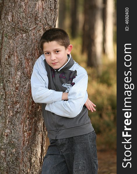 A teenage boy leaning against a tree with a look of attitude. A teenage boy leaning against a tree with a look of attitude