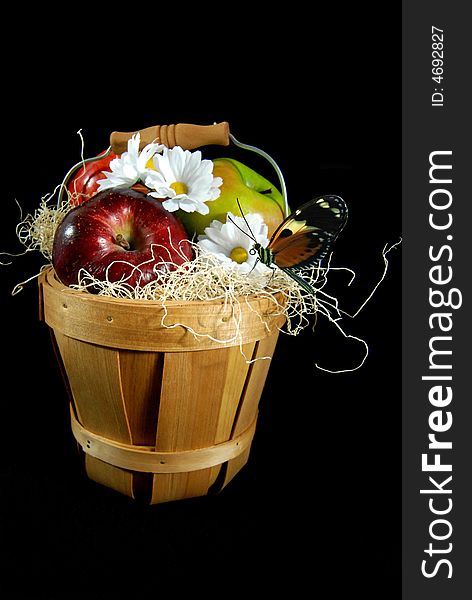 Basket of fresh apples with a butterfly and daisies on a black background. Basket of fresh apples with a butterfly and daisies on a black background.