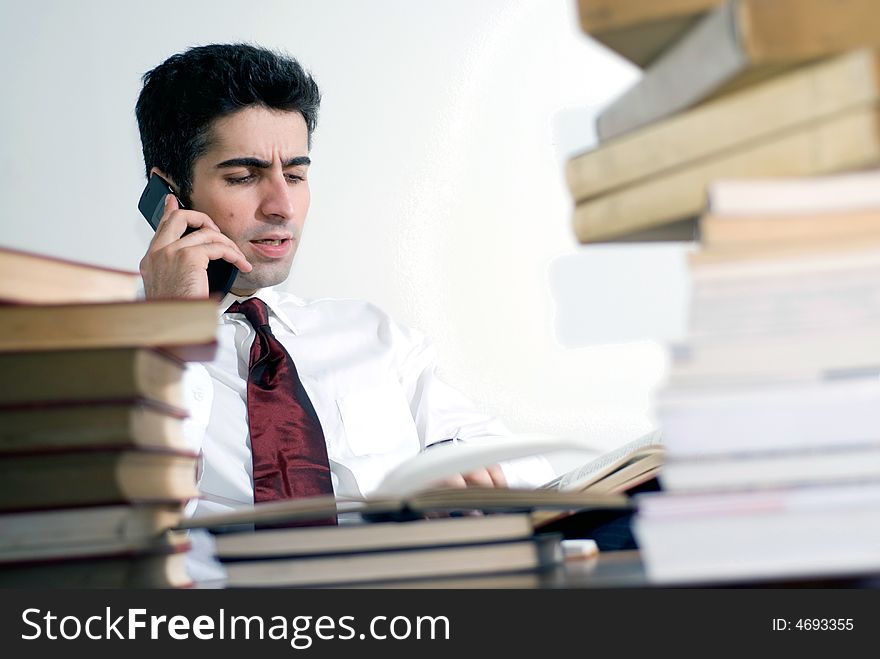 Man in business attire on the phone surrounded by books