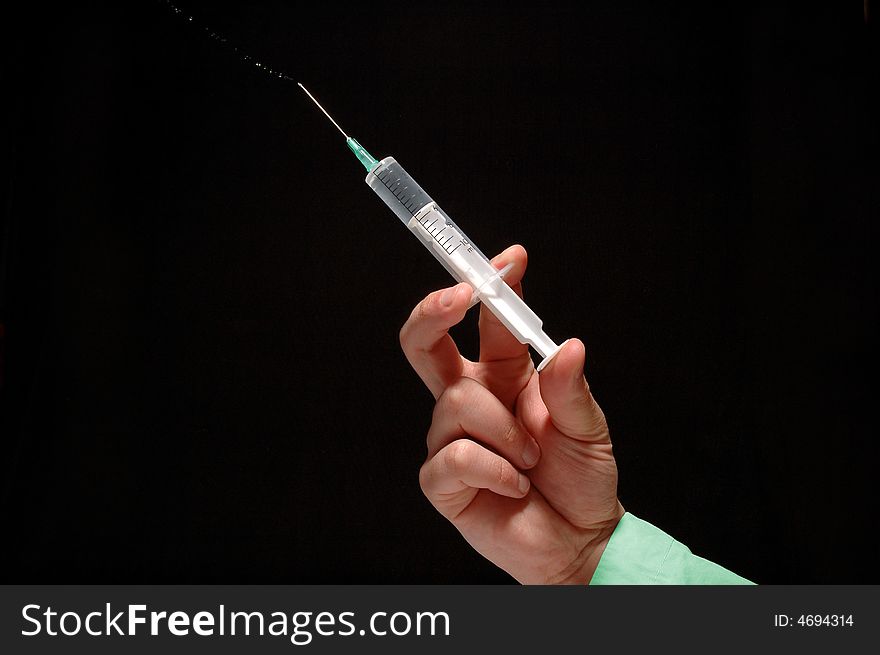 Doctor’s hand holding syringe isolated on black. Doctor’s hand holding syringe isolated on black