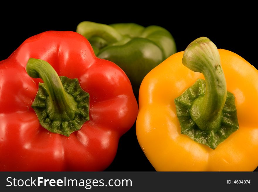 Red yellow and green Bell Peppers on a black background