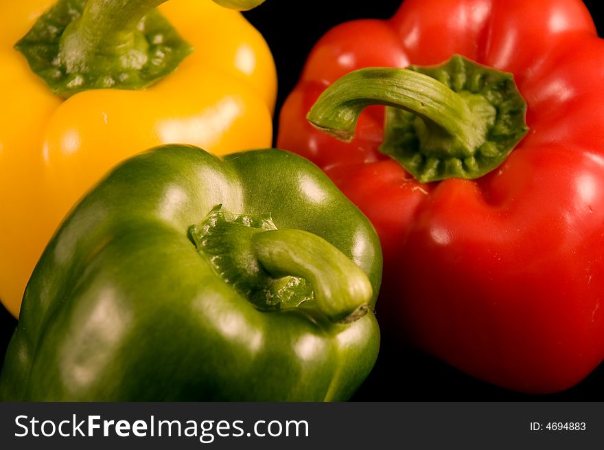 Red yellow and green Bell Peppers on a black background