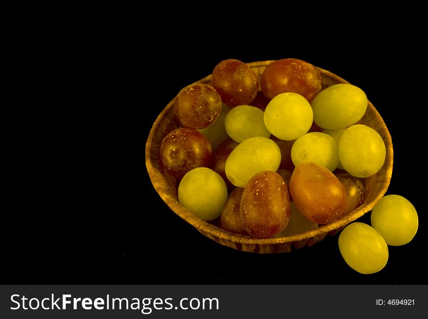 Small punnet of red and green grapes on a black background. Small punnet of red and green grapes on a black background