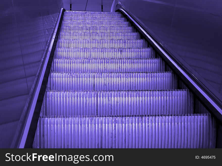 Going up a shiny metal staircase, escalator, empty, finished with blue tine