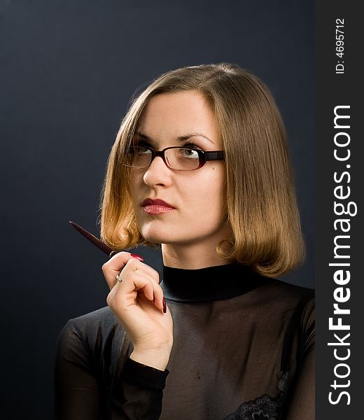 Portrait of girl with glasses and pen at hand on black background
