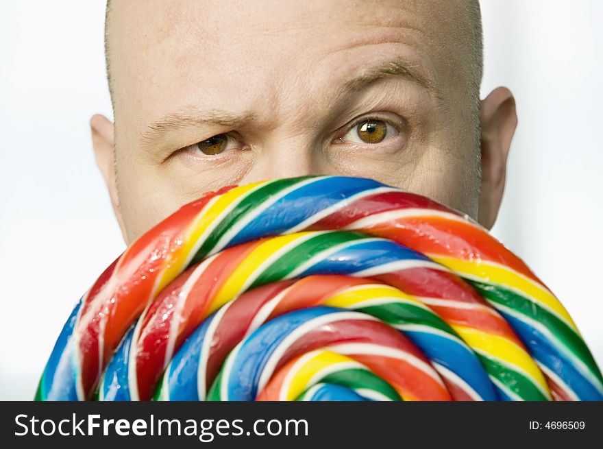 Bald man stares from behind a colorful lollipop. Bald man stares from behind a colorful lollipop