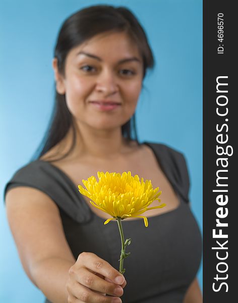 A pretty young woman offering a yellow flower, with the focus on the flower. A pretty young woman offering a yellow flower, with the focus on the flower.