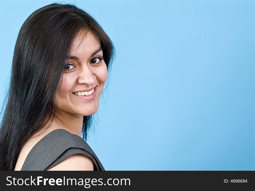 A pretty young woman smiling coyly for the camera taken against a blue background with copy space. A pretty young woman smiling coyly for the camera taken against a blue background with copy space.