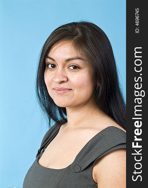 A portrait of a young, naturally beautiful Hispanic woman taken against a blue background. A portrait of a young, naturally beautiful Hispanic woman taken against a blue background.