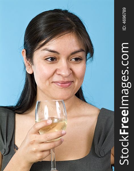 A smiling, contented, pretty young woman holding a wine glass with liquid in it. A smiling, contented, pretty young woman holding a wine glass with liquid in it.