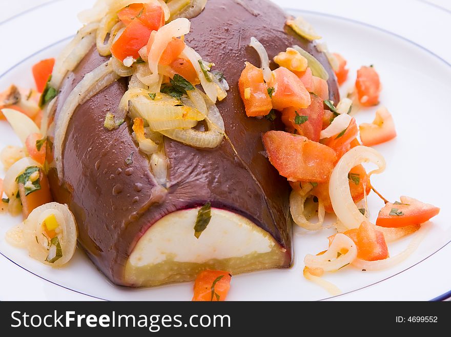 An cooked Aubergine or eggplant with vegetables against a white background