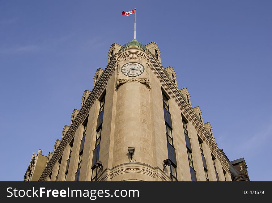 Distorted Perspective of a wedge shaped building, clock face and Canadian flag at the top