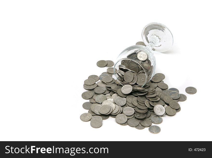 Wineglass with coins poured out over a white background. Wineglass with coins poured out over a white background