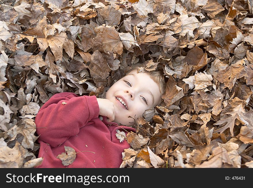 Boy laying in pile of leaves. Boy laying in pile of leaves