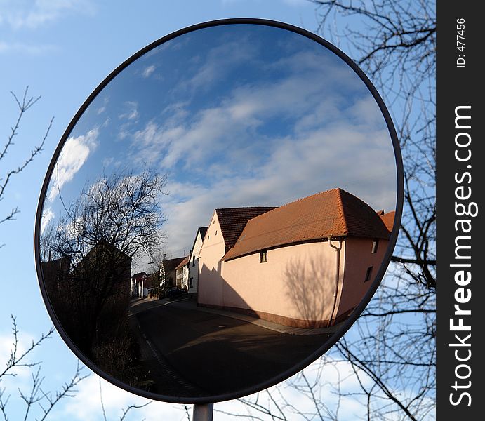 An empty village street and houses seen through a street-side mirror in the Palatinate area of Germany on a cold winter day. An empty village street and houses seen through a street-side mirror in the Palatinate area of Germany on a cold winter day