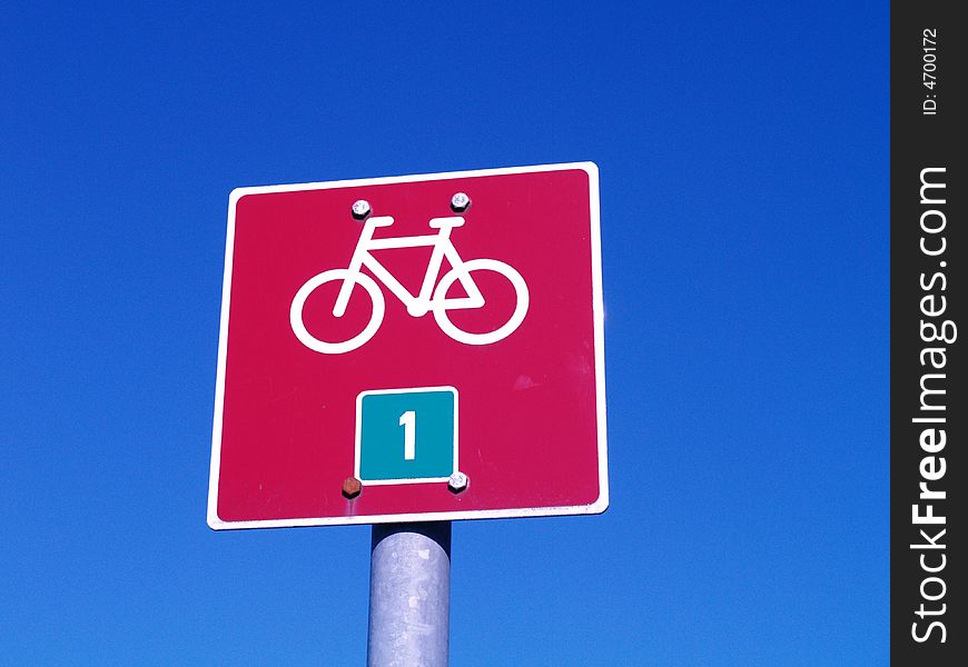 Red bicycle sign on blue sky background