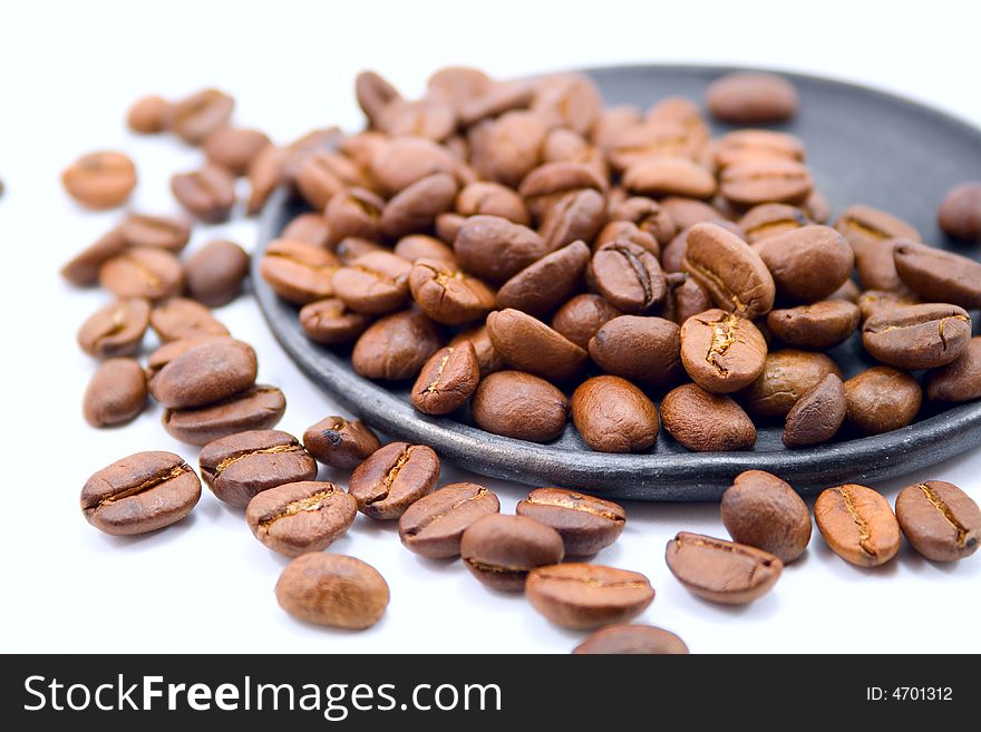 Roasted coffee beans laying on the black plate. Roasted coffee beans laying on the black plate