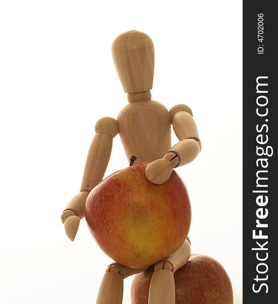 Mannequin with two apples one being held and the other being sat upon. Mannequin with two apples one being held and the other being sat upon