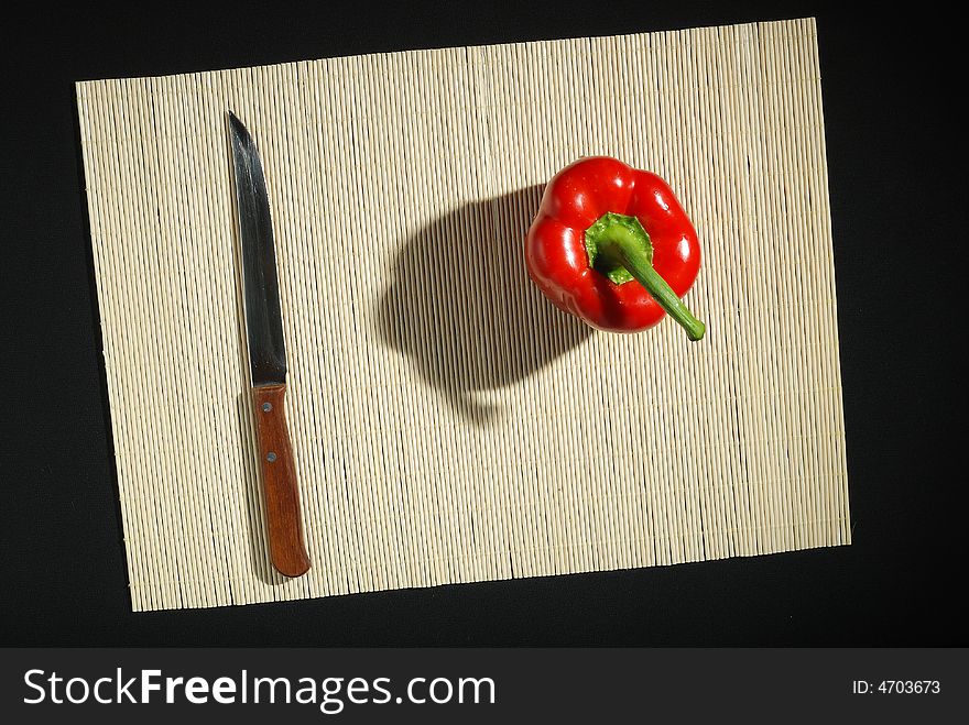 Red bell pepper and knife on a mat