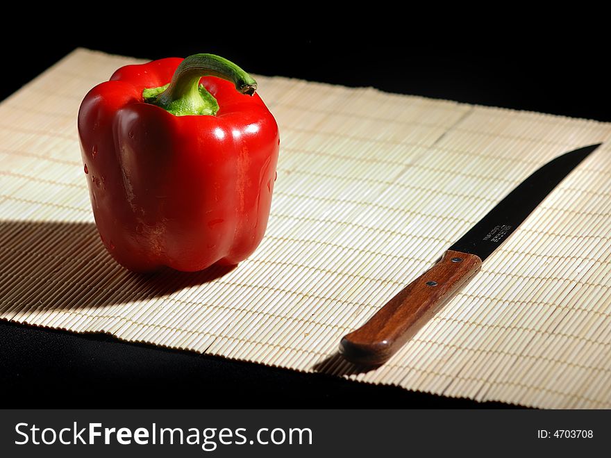 Red bell pepper and knife on a mat