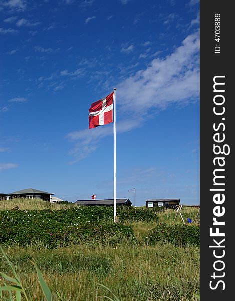 A danish flag in typical danish sommerhouse surroundings. A danish flag in typical danish sommerhouse surroundings