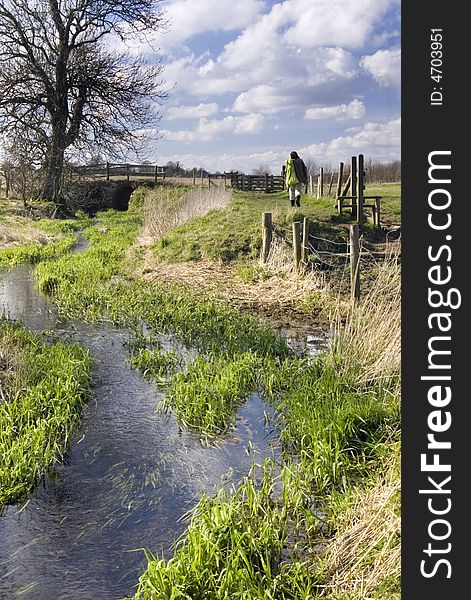 A person walking along the stream in a countryside, Avebury, Wilthshire, England meadow meadows. A person walking along the stream in a countryside, Avebury, Wilthshire, England meadow meadows