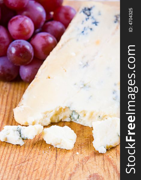 Blue stilton cheese with grapes on a wooden board