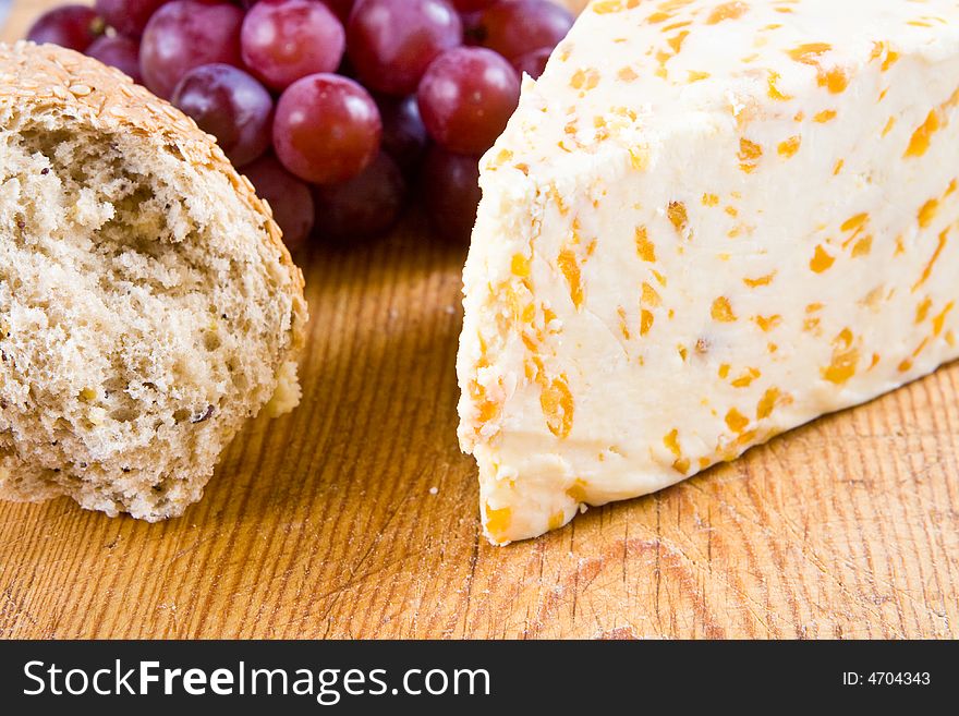 Apricot stilton cheese with grapes and bread on a wooden board