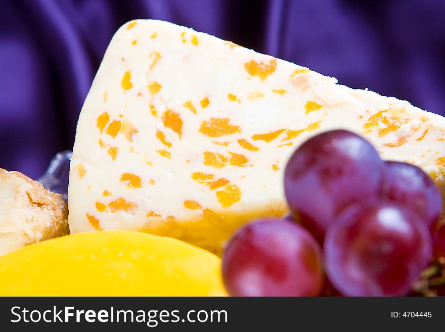 Apricot stilton cheese and grapes with a silk background. Apricot stilton cheese and grapes with a silk background